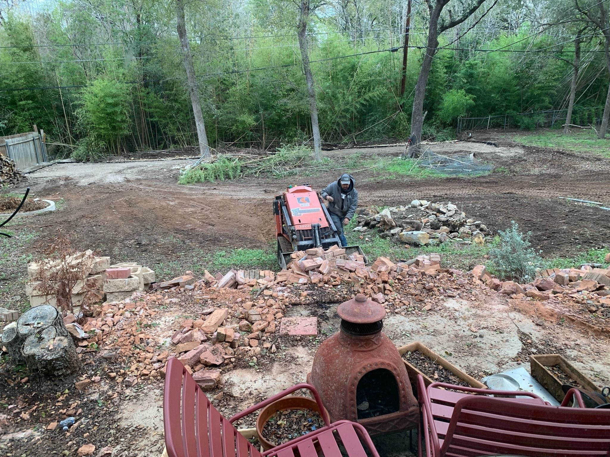 picture of a man on a machine in a backyard filled with rubble and trampled bamboo
